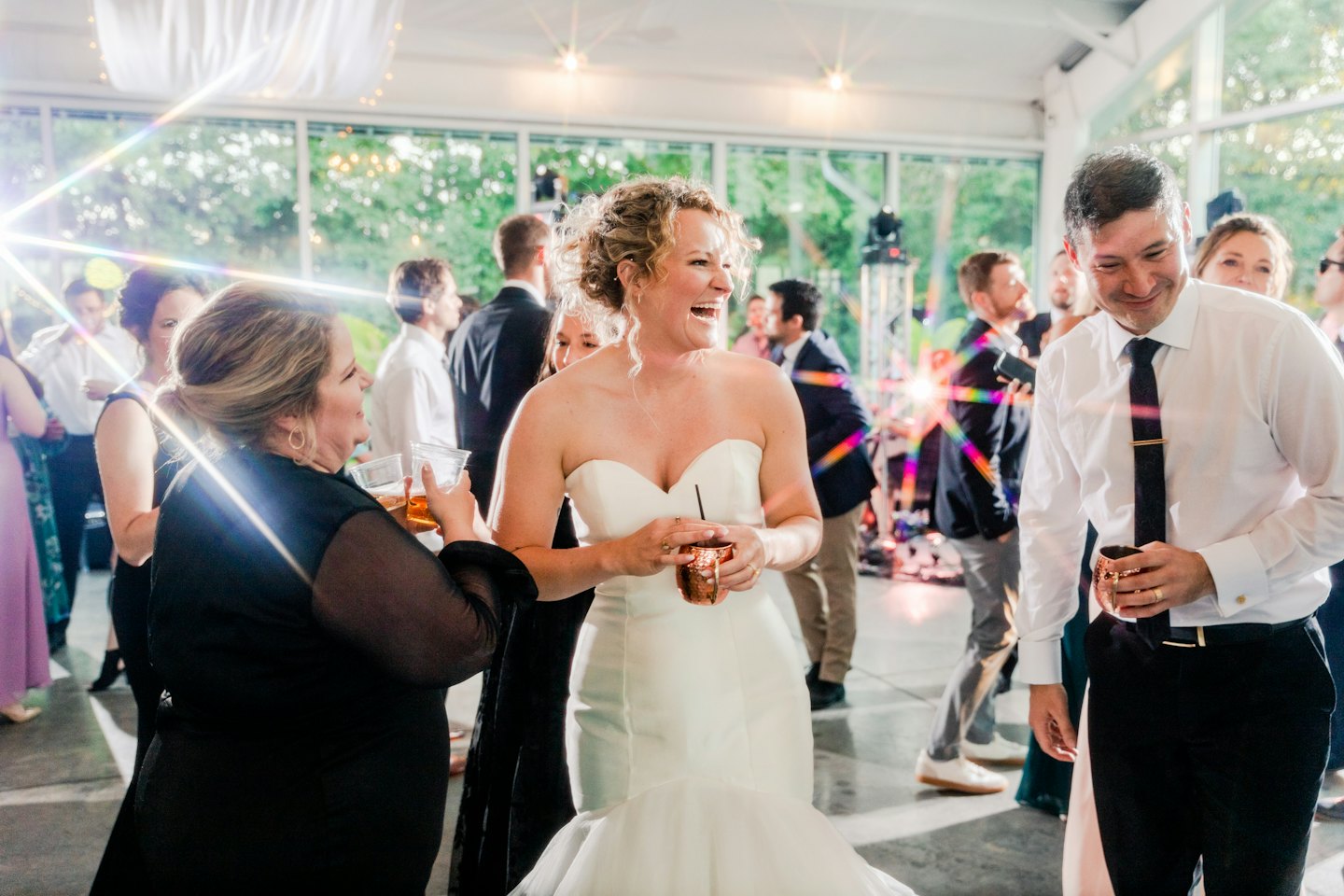 La mariée rit avec des invités lors de la réception de mariage.