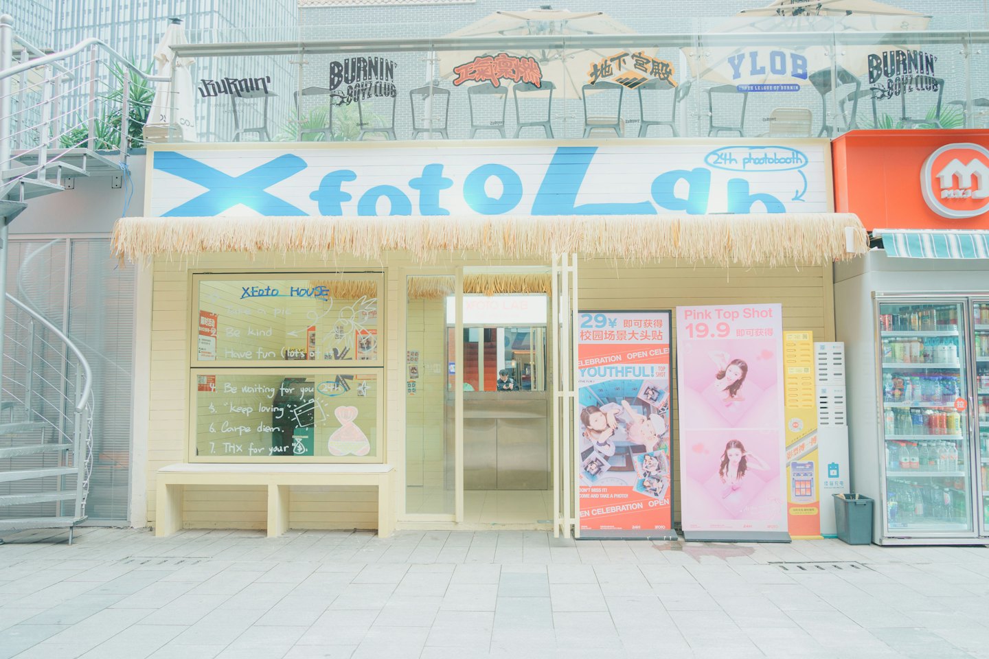 Façade du magasin Xfoto Lab avec un toit de chaume et des bannières promotionnelles.