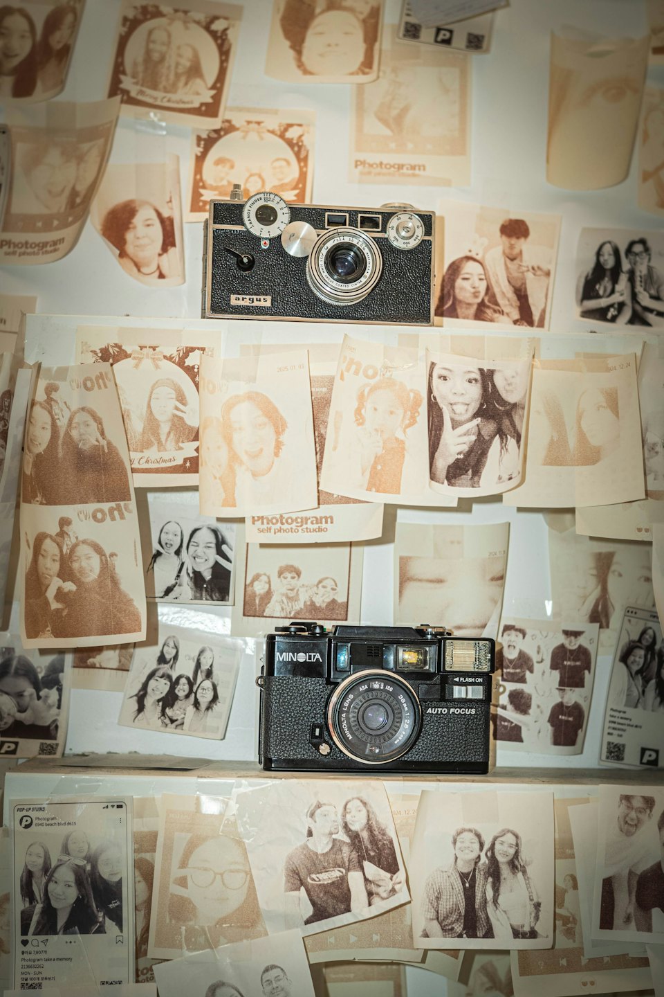 Appareils photo vintage exposés parmi de nombreuses photos encadrées sur un mur.